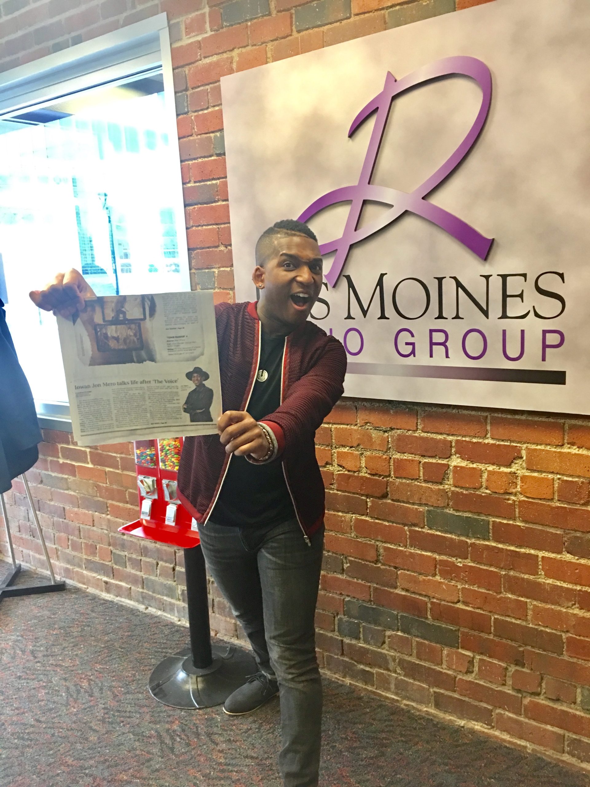 Jon Metro holding a newspaper feature at Des Moines Radio Group